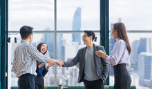Asian Business Team Leader Congratulate His Teammate Employee For The Outstanding Achievement Team Performance By Shaking Hand In The Modern Office Workplace With Skyscraper View