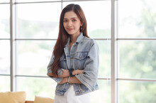 Portrait Closeup Shot Of Asian Young Beautiful Long Brown Hair Female Teenager Fashion Model In Casual Blue Street Denim Jeans Jacket Standing Smiling Look At Camera Holding Hand At Chin Crossed Arm