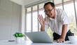 Asian old senior happy friendly male businessman in business outfit with glasses waving hand smiling say hello greeting with customer via video call conference from laptop computer in company office