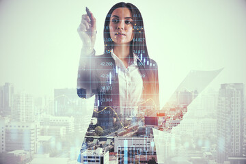 Poster - Attractive young european businesswoman with document on bright city background pointing at candlestick forex grid chart with pen. Trade, finance and economy concept. Double exposure.