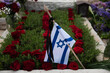 © Yehoshua Halevi - A small, blue and white flag of the State of Israel placed at the foot of a grave covered with red roses in the Har Herzl military cemetery in Jerusalem.