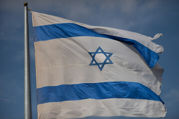 Wall Mural - A large, blue and white flag of the State of Israel rippling in the wind on a sunny day during the national observance of the Independence and Memorial day holidays.