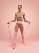 © opolja - Sportswoman exercising with resistance band. Female with working out with elastic band on pink background