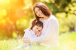 Happy mother and daughter in the spring park. Beauty nature scene with summer outdoor lifestyle. Happy family resting together on green grass, having fun outdoor. Happiness and harmony in family life