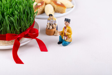 Wall Mural - Green fresh semeni sabzi wheat grass in white plate decorated with red ribbon with wooden shebeke pattern, Novruz spring equinox celebration in Azerbaijan
