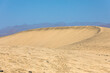Runde Sanddüne aus Wüstensand in der Dünenlandschaft auf Maspalomas vor den Bergen von Gran Canaria