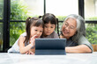 © Prot - Asian Grandmother with her two grandchildren having fun and playing education games online with a digital tablet at home in the living room. Concept of online education and caring from parents.