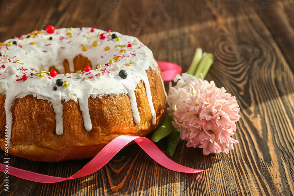 Tasty Easter cake with flowers on wooden background, closeup