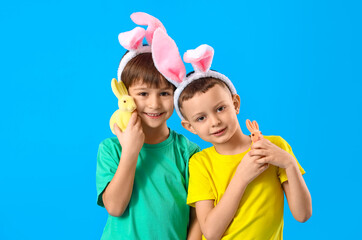 Poster - Cute little boys with bunny ears and toy rabbits on blue background