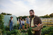 © Halfpoint - Happy mature man carrying crate with homegrown vegetables at community farm.