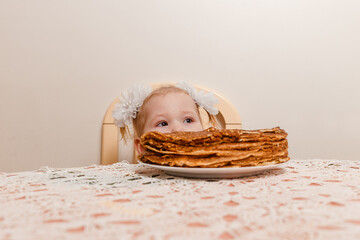 a two-year-old girl bites pancakes. Maslenitsa festival