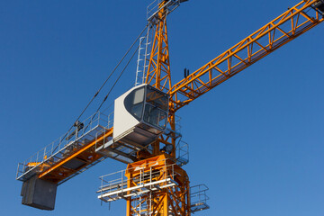 Poster - Tower crane against the blue sky. Tower crane operator's cabin. Crane operator at work.