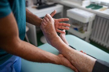 Wall Mural - close-up of physiotherapist exercising with senior patient's leg in a physic room.