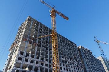 Poster - Residential building construction. Crane and building construction site against blue sky.