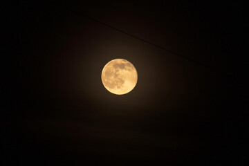 Wall Mural - The full moon is yellow against the background of the night black sky, a hanging wire from buildings