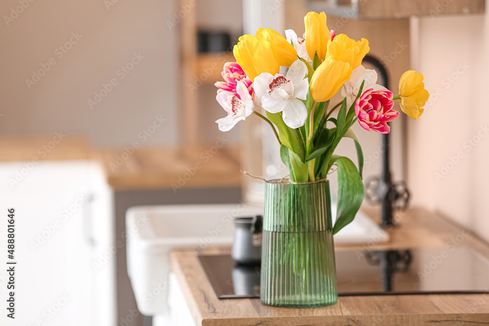 Vase with flowers on wooden kitchen counter