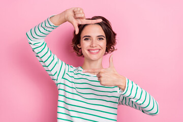 Poster - Portrait of attractive cheerful funny girl showing photo frame isolated over pink pastel color background