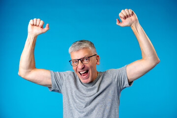 Middle aged man happy and excited celebrating success over blue background