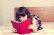 © gmstockstudio - Little girl reading a book at home