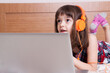 © gmstockstudio - Little girl using the laptop with earphones