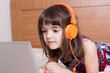 © gmstockstudio - Little girl using the laptop with earphones
