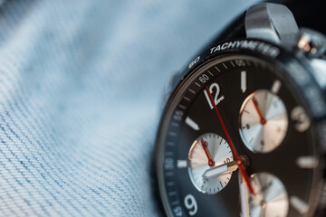 Expensive luxury watch with chronograph and clock on jeans texture, close-up. Business and success concept