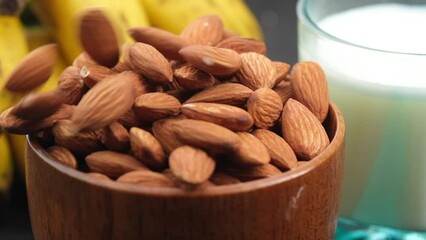 Poster - Close up of almond nuts in a bowl , banana and milk on table 