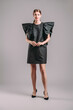 © Love-Pics - Oversize dress in black. Elegant cocktail midi dress with ruffles on massive shoulders. Beautiful young lady posing in studio. Elegant female fashion, summer evening look.