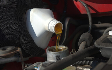 new transparent yellow engine oil is poured into a car engine