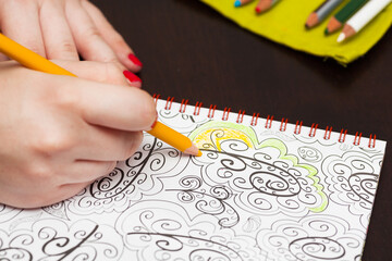 Wall Mural - Woman's hands coloring adult color book as stress relief.