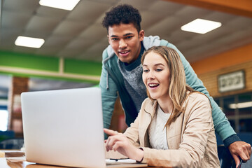 Heres all the information at out fingertips. Shot of a young man looking on while a female student works on a laptop.