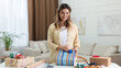 © New Africa - Beautiful young woman wrapping gift at table in living room