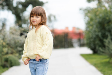 Cute little baby girl 4-5 year old wear casual clothes walk in park outdoor. Looking at camera. Springtime. Childhood.