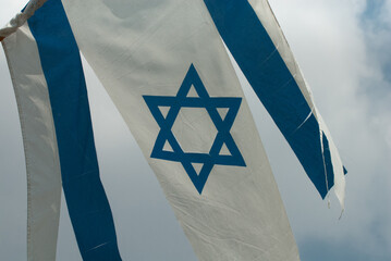 Wall Mural - A torn and shredded blue and white flag of the State of Israel hangs from a pole on the side of a building in Jerusalem. .