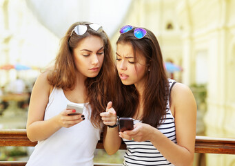 Two young  women chatting in a street cafe,Teenage girl using smart phone.Selfie