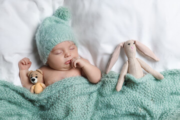 Sticker - Cute little baby with toys sleeping under knitted plaid in bed, top view