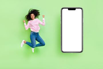 Wall Mural - Full length view of cheerful lucky girl jump rejoice win cellphone ads poster isolated bright green color background