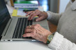 Elderly woman using the laptop - closeup on the hand