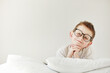 © Andriy Medvediuk - Adorable smiling child boy in glasses is lying in bed. morning dreaming on white bed.
