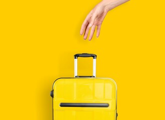 Canvas Print - Female hand holds a suitcase on a bright yellow background