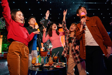 Group of happy asian friends are having fun, singing in karaoke club