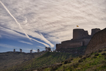 Canvas Print - A beautiful shot of old windmills and a castle under a blue cloudy sky on a sunny day