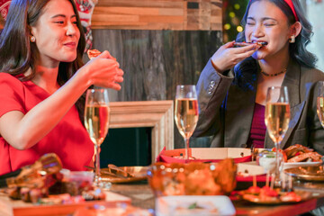 Wall Mural - Party of beautiful asian friend female celebrating. women eating pizza on table with snack and drink. happiness friends christmas eve celebration dinner party food and champagne.