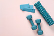 Dumbless, foam roller and fitness tapes on pastel pink background. Sport workout equipment, top view.