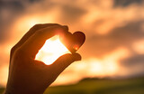 Fototapeta Na ścianę - Hand holding up heart to sunset sky. Love and compassion concept. 