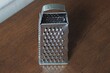 one gray metal kitchen grater stands on a brown table
