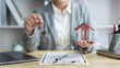© snowing12 - Insurance concept the real estate representative holding a house key on the right hand and the house model on the left hand
