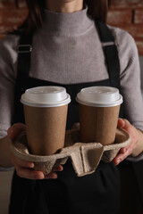 Canvas Print - Barista holding takeaway paper cups with coffee in cafe, closeup