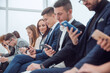 © ASDF - group of young business people looking at their smartphone screens.