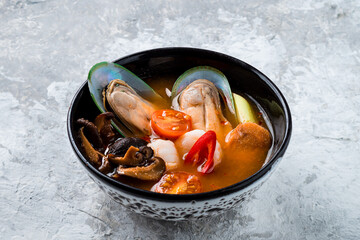 Sticker - Traditional spicy Thai soup Tom Yum with shrimp and seafood in ceramic bowl on stone background